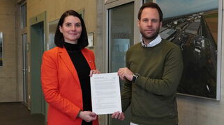 Geschäftsführer Sven Pennings übergibt das Commitment der AGIT zum Klimastadtvertrag an Dr. Carin Jansen